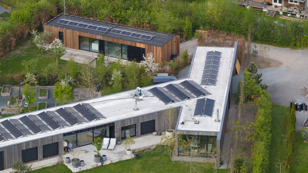 Aerial view of Ecodorp Bolderburen featuring modern wooden houses with solar panels on flat roofs and lush gardens in Almere Flevoland Netherlands. Aerial view of Ecodorp Bolderburen featuring modern wooden houses with solar panels on flat roofs and lush gardens in Almere Flevoland Netherlands.