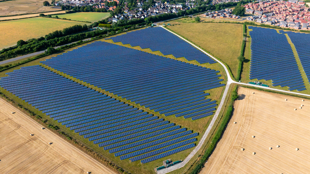 Aerial view of a large solar farm with rows of photovoltaic panels situated in rural fields near a residential area in Dorset England United Kingdom. Aerial view of a large solar farm with rows of photovoltaic panels situated in rural fields near a residential area in Dorset England United Kingdom.