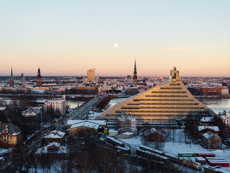Aerial view of the National Library of Latvia building during sunset with a full moon visible in the sky over the snow covered city and Daugava river Riga Latvia. Aerial view of the National Library of Latvia building during sunset with a full moon visible in the sky over the snow covered city and Daugava river Riga Latvia.