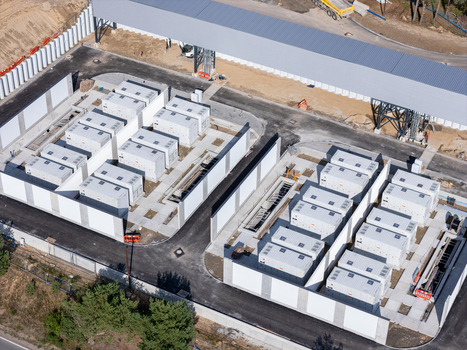 Aerial view of a battery energy storage system facility with rows of white containers and concrete walls in Poland.