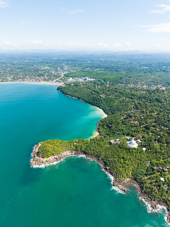 Aerial view of Jungle Beach and the Japanese Peace Pagoda surrounded by lush tropical forest and turquoise waters in Unawatuna Sri Lanka. Aerial view of Jungle Beach and the Japanese Peace Pagoda surrounded by lush tropical forest and turquoise waters in Unawatuna Sri Lanka.