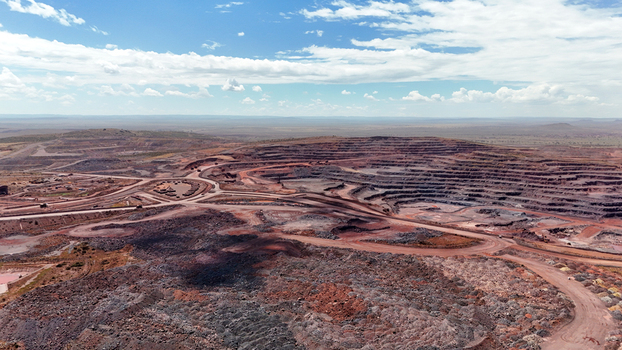 Aerial view of the vast arid landscape scarred by the geometric patterns of a mining operation its layers of rust red earth contrasting with the pale sky North West South Africa. Aerial view of the vast arid landscape scarred by the geometric patterns of a mining operation its layers of rust red earth contrasting with the pale sky North West South Africa.