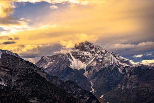 Aerial view of Croda Rossa peaks piercing through a golden sky dusted with snow and shadowed by dramatic clouds Cortina d Ampezzo Veneto Italy. Aerial view of Croda Rossa peaks piercing through a golden sky dusted with snow and shadowed by dramatic clouds Cortina d Ampezzo Veneto Italy.