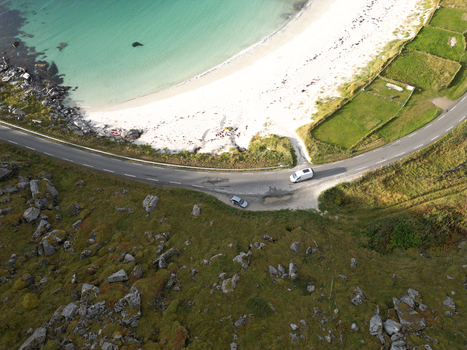 Aerial view of Vik Strand beach featuring turquoise water white sand and a coastal road winding through rocky green hills in Leknes Nordland Norway. Aerial view of Vik Strand beach featuring turquoise water white sand and a coastal road winding through rocky green hills in Leknes Nordland Norway.