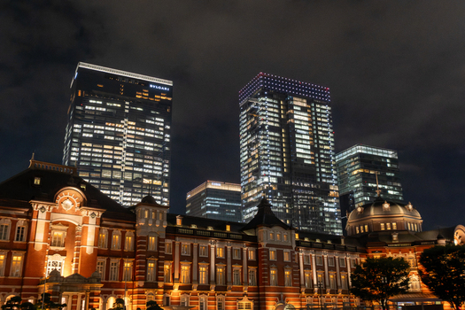 View of illuminated Tokyo Station a striking contrast of historic red brick against modern glowing skyscrapers under a dark cloudy sky Tokyo Tokyo Japan. View of illuminated Tokyo Station a striking contrast of historic red brick against modern glowing skyscrapers under a dark cloudy sky Tokyo Tokyo Japan.