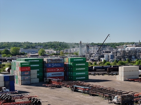 Cincinnati United States 19 April 2026 Aerial view of stacked shipping containers at a logistics terminal with an industrial facility and cranes in the background.
