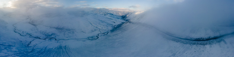 Aerial view of the snow covered Babusar Pass with a winding road through rugged mountain peaks under thick clouds in Babusar KPK Pakistan.