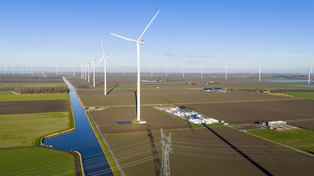 Aerial view of wind turbines in a field with a canal and power lines in Dronten Flevoland Netherlands.