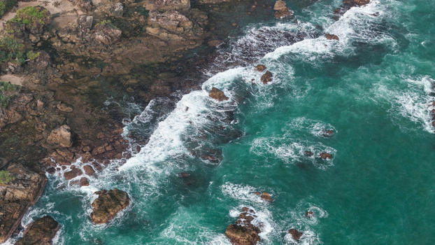 Aerial view of rocky coastline with turquoise water and crashing waves in Indonesia. Aerial view of rocky coastline with turquoise water and crashing waves in Indonesia.
