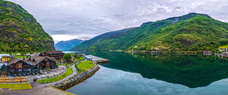 Aerial view of the village of Flam nestled along the Aurlandsfjord featuring wooden buildings lush green mountains and calm reflective water in Flam Vestland Norway. Aerial view of the village of Flam nestled along the Aurlandsfjord featuring wooden buildings lush green mountains and calm reflective water in Flam Vestland Norway.