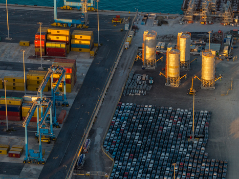 Civitavecchia Lazio Italy 23 August 2026 Aerial view of Civitavecchia Port terminal with stacked shipping containers industrial silos and rows of parked cars during golden hour.