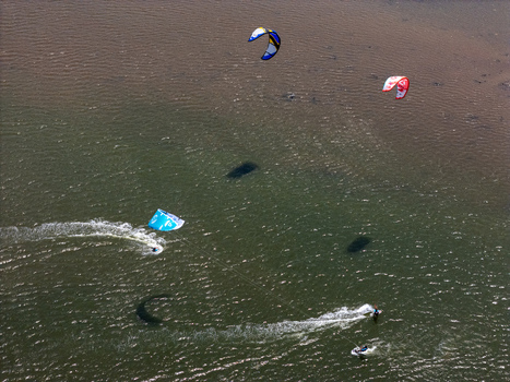 Aerial view of kitesurfers gliding across the water at Depok Beach with vibrant kites and wakes in the sea Special Region of Yogyakarta Indonesia.