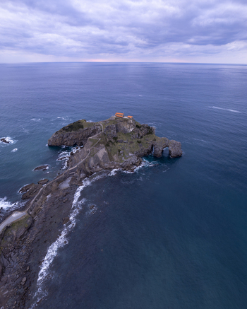 Aerial view of San Juan de Gaztelugatxe a historic hermitage on a rocky islet connected by a stone bridge surrounded by the Cantabrian Sea in Gaztelugatxeko Doniene Euskadi Spain.