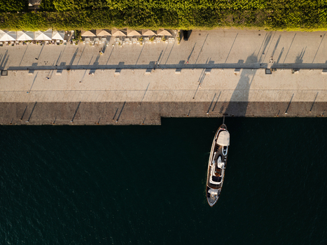 Aerial view of the Island of Ortigia waterfront with a docked boat and long shadows on the promenade in Syracuse Sicily Italy. Aerial view of the Island of Ortigia waterfront with a docked boat and long shadows on the promenade in Syracuse Sicily Italy.
