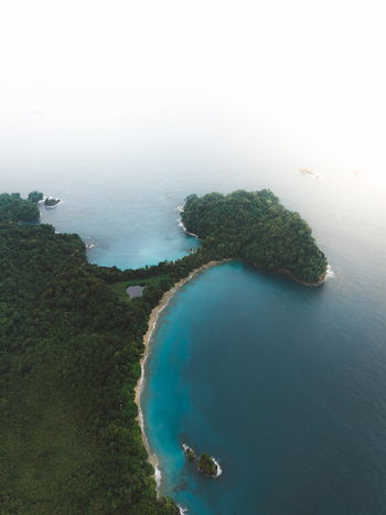 Aerial view of a lush green coastline with turquoise waters a sandy beach and small rocky islets in Costa Rica.