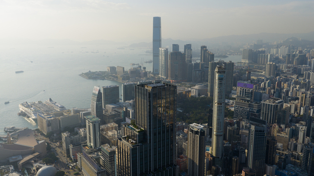 Aerial view of the dense skyline of Tsim Sha Tsui and Victoria Harbour with the International Commerce Centre towering over the city under a hazy sky Hong Kong Hong Kong. Aerial view of the dense skyline of Tsim Sha Tsui and Victoria Harbour with the International Commerce Centre towering over the city under a hazy sky Hong Kong Hong Kong.