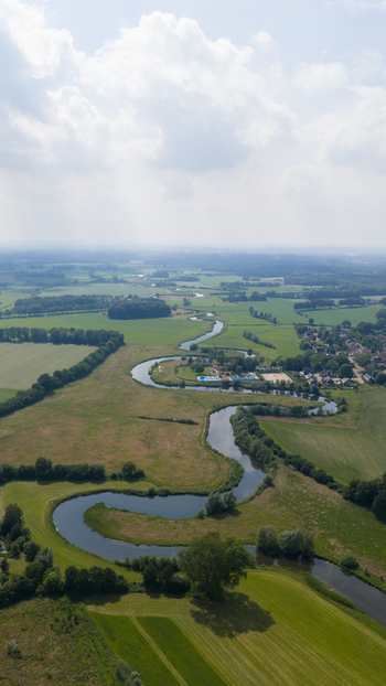 Aerial view of the winding Berkel river flowing through the lush green meadows and agricultural fields of the Dutch countryside in Almen Gelderland Netherlands. Aerial view of the winding Berkel river flowing through the lush green meadows and agricultural fields of the Dutch countryside in Almen Gelderland Netherlands.