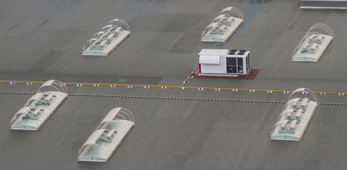 Aerial view of a modern industrial rooftop featuring arched skylights and HVAC cooling equipment showcasing clean geometric composition and commercial building infrastructure Valence Auvergne Rhone Alpes France.