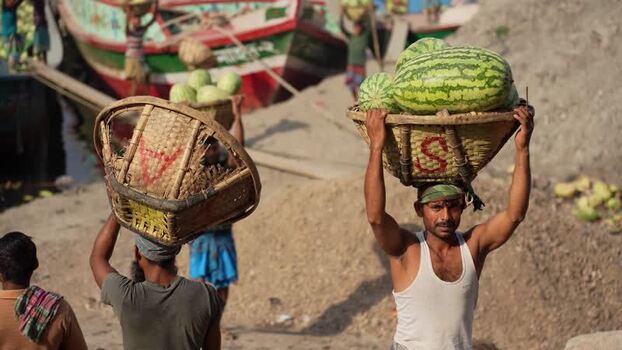View of workers carrying watermelons at Sadarghat port Bangladesh.