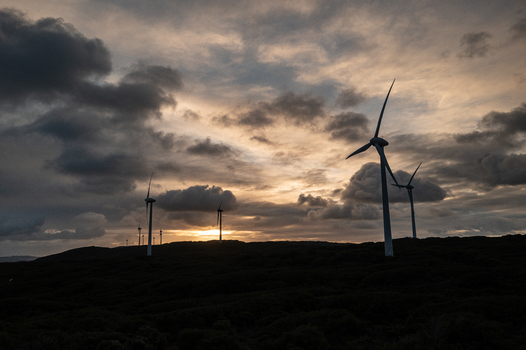 View of the Sandpatch wind farm with large turbines silhouetted against a dramatic sunset sky over the rugged coastal landscape in Sandpatch Western Australia Australia. View of the Sandpatch wind farm with large turbines silhouetted against a dramatic sunset sky over the rugged coastal landscape in Sandpatch Western Australia Australia.