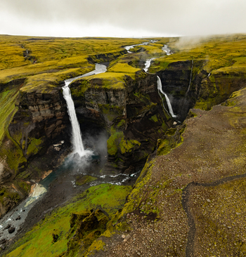 Aerial view of the dramatic Haifoss waterfall cascading into a deep canyon surrounded by lush green mossy cliffs and rugged volcanic terrain in Skeida og Gnupverjah Iceland. Aerial view of the dramatic Haifoss waterfall cascading into a deep canyon surrounded by lush green mossy cliffs and rugged volcanic terrain in Skeida og Gnupverjah Iceland.