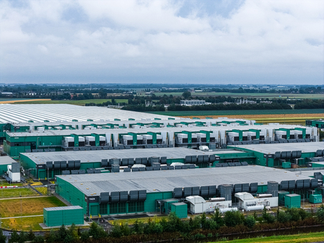 Aerial view of Agriport A7 data center with large green buildings and rooftop HVAC units surrounded by agricultural fields in Middenmeer Noord Holland Netherlands. Aerial view of Agriport A7 data center with large green buildings and rooftop HVAC units surrounded by agricultural fields in Middenmeer Noord Holland Netherlands.