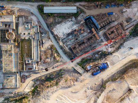 Aerial view of resort development under construction with a large red crane building foundations and exposed earth in Kecamatan Kuta Selatan Bali Indonesia. Aerial view of resort development under construction with a large red crane building foundations and exposed earth in Kecamatan Kuta Selatan Bali Indonesia.