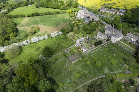 Aerial view of Snowshill Manor and its historic gardens surrounded by lush green fields and trees in the Cotswolds in Snowshill England United Kingdom.