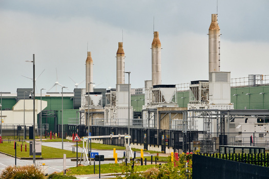 Middenmeer Netherlands 17 May 2026 View of the Microsoft datacenters on Agriport with tall exhaust stacks and wind turbines under an overcast sky.
