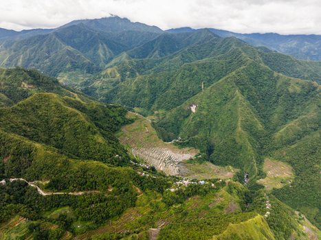 Aerial view of the Batad Rice Terraces nestled within lush green mountains and a small village Banaue Cordillera Administrative Region Philippines.