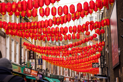 London United Kingdom 12 May 2025 View of vibrant red Chinese lanterns hanging across a street in Chinatown surrounded by historic brick buildings and shop signs.