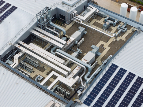 Aerial view of a data center roof featuring complex HVAC ventilation systems industrial cooling units and rows of solar panels in the United Kingdom.