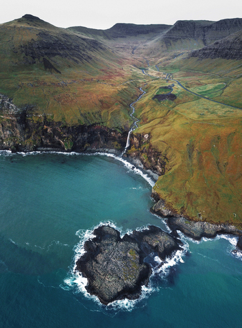 Aerial view of mountain waterfall Skar&eth;s&aacute;fossur flowing into the Atlantic Ocean surrounded by mountains on V&aacute;gar in the Faroe Islands Denmark