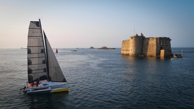 Aerial view of a sleek sailboat gliding past the imposing Ch&acirc;teau du Taureau fortress its stone walls reflecting the calm sea Plouezoc h Bretagne France.
