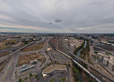 Aerial view of the urban landscape featuring highway interchanges railway tracks with a freight train and commercial buildings under a cloudy sky in Denver Colorado United States. Aerial view of the urban landscape featuring highway interchanges railway tracks with a freight train and commercial buildings under a cloudy sky in Denver Colorado United States.