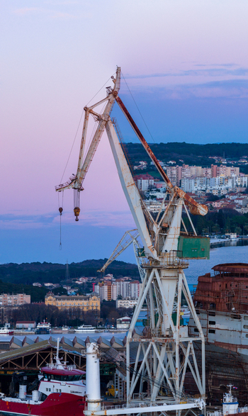 Aerial view of the iconic Uljanik Shipyard with its large industrial cranes docked ships and the coastal cityscape of Pula Croatia.