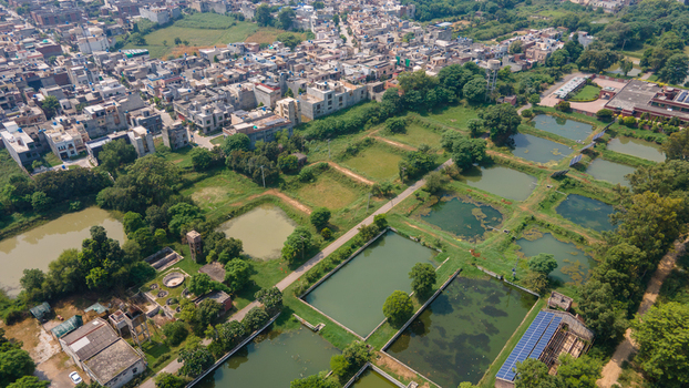 Aerial view of a fishing farm with rectangular ponds lush green surroundings and nearby residential buildings in Punjab Pakistan. Aerial view of a fishing farm with rectangular ponds lush green surroundings and nearby residential buildings in Punjab Pakistan.