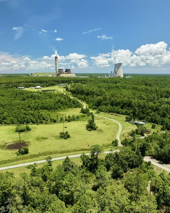 Aerial view of the Seminole Electric power plant with its cooling tower and chimney rising above the surrounding forest and rural landscape in Palatka Florida United States.