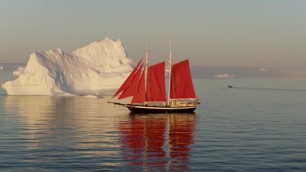 Aerial view of sailboat with red sails near iceberg Greenland. Aerial view of sailboat with red sails near iceberg Greenland.