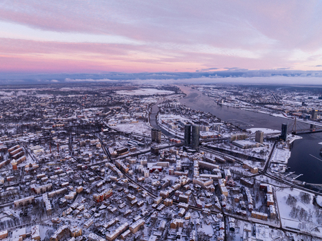 Aerial view of the city of Riga covered in snow during a winter sunrise with the Daugava River flowing through the urban landscape Riga Latvia.