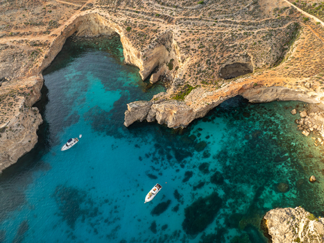Aerial view of azure waters meeting rugged cliffs and boats a tranquil scene from above the Blue Lagoon Comino Malta. Aerial view of azure waters meeting rugged cliffs and boats a tranquil scene from above the Blue Lagoon Comino Malta.