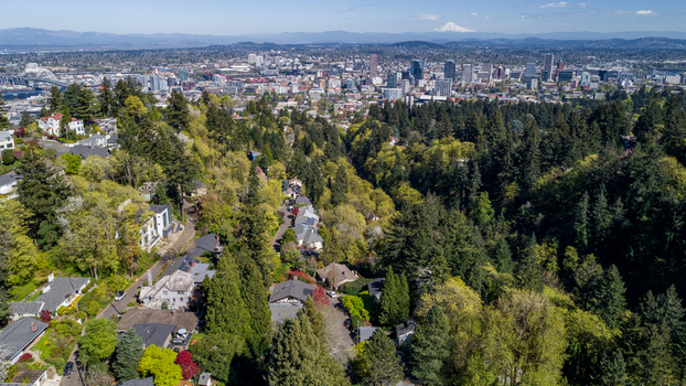 Aerial view of Southwest Imperial Drive residential area with lush green trees the city skyline and Mount Hood in the distance in Portland Oregon United States. Aerial view of Southwest Imperial Drive residential area with lush green trees the city skyline and Mount Hood in the distance in Portland Oregon United States.