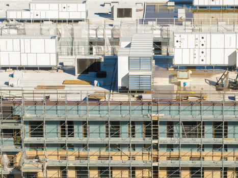 Aerial view of a building under construction with extensive scaffolding covering the facade and numerous HVAC units installed on the flat roof in Ancona Marche Italy. Aerial view of a building under construction with extensive scaffolding covering the facade and numerous HVAC units installed on the flat roof in Ancona Marche Italy.