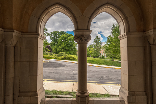 Washington United States 06 May 2025 View of Washington National Cathedral through stone arches with a view of the surrounding grounds and trees.