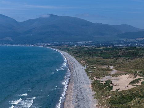 Aerial view of the coastline at Newcastle beach with the Mourne Mountains in the background sand dunes and blue sea in Newcastle Northern Ireland United Kingdom. Aerial view of the coastline at Newcastle beach with the Mourne Mountains in the background sand dunes and blue sea in Newcastle Northern Ireland United Kingdom.