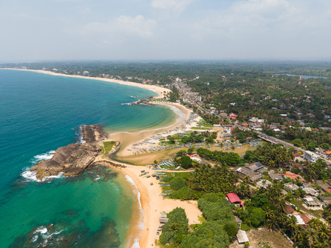 Aerial view of the tropical coastline with sandy beaches turquoise ocean waters and traditional fishing boats scattered along the shore in Dodanduwa Southern Province Sri Lanka. Aerial view of the tropical coastline with sandy beaches turquoise ocean waters and traditional fishing boats scattered along the shore in Dodanduwa Southern Province Sri Lanka.