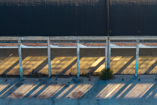 Aerial view of a warehouse with brick and concrete pillars casting long shadows across the concrete ground in Warsaw Masovian Voivodeship Poland.