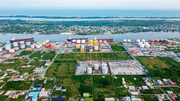 Aerial view of the industrial port area in Satellite Town with large oil storage tanks cargo ships docked along the waterfront and surrounding urban development in Lagos Lagos Nigeria.
