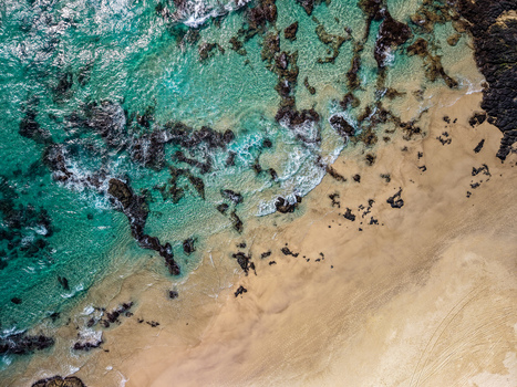 Aerial view of Cudgen Headland South Head showing turquoise ocean waves crashing against dark volcanic rocks and golden sandy beach in Kingscliff New South Wales Australia. Aerial view of Cudgen Headland South Head showing turquoise ocean waves crashing against dark volcanic rocks and golden sandy beach in Kingscliff New South Wales Australia.