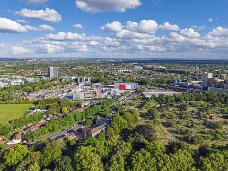 Aerial view of the town of Brentford featuring urban development green spaces and industrial buildings under a bright blue sky with scattered clouds in Brentford England United Kingdom. Aerial view of the town of Brentford featuring urban development green spaces and industrial buildings under a bright blue sky with scattered clouds in Brentford England United Kingdom.